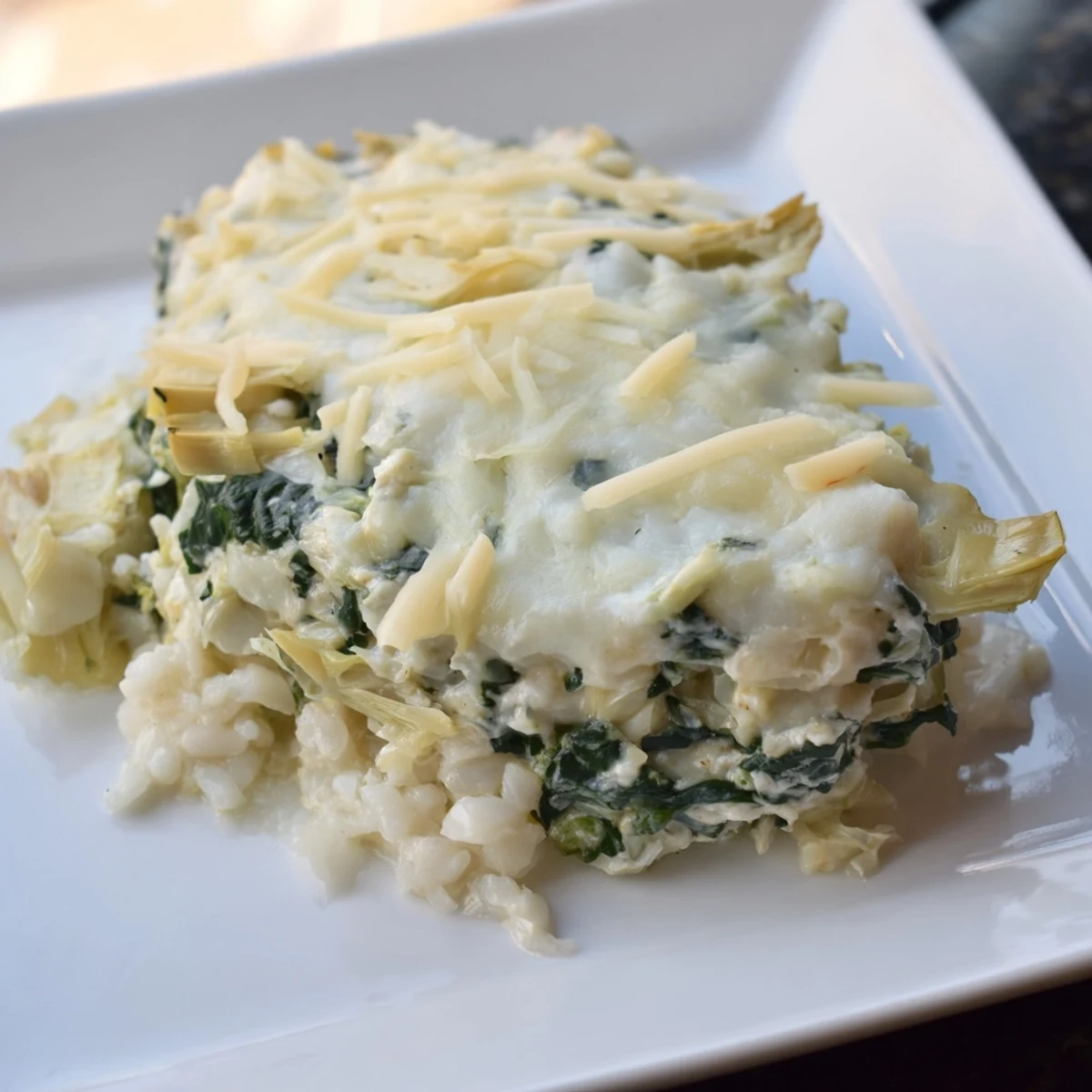 Creamy Cheesy Spinach and Artichoke Bake, ready to scoop, featuring visible artichoke pieces and melted mozzarella.