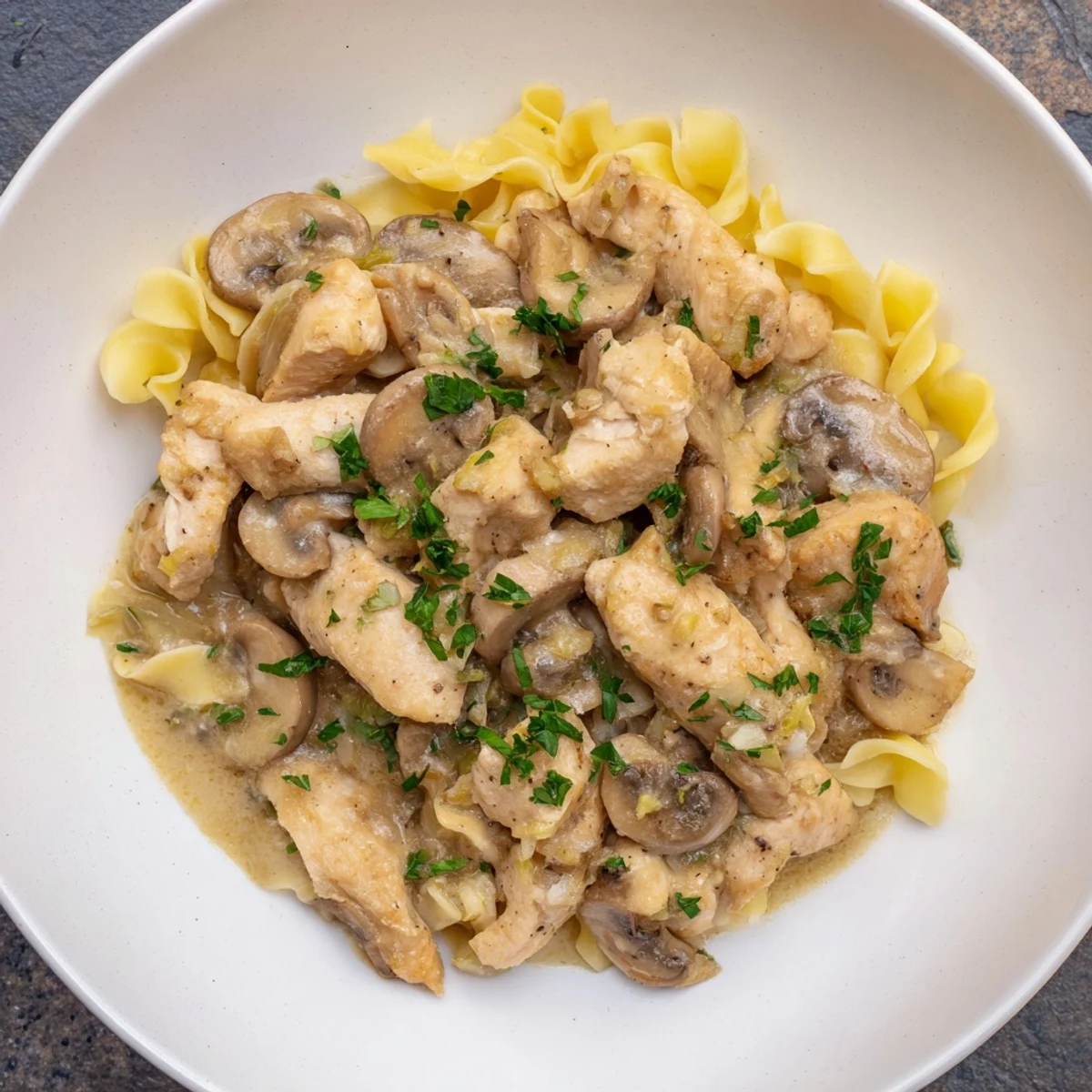 A steaming bowl of Creamy Chicken Stroganoff, the rich sauce clinging to tender chicken and mushrooms.