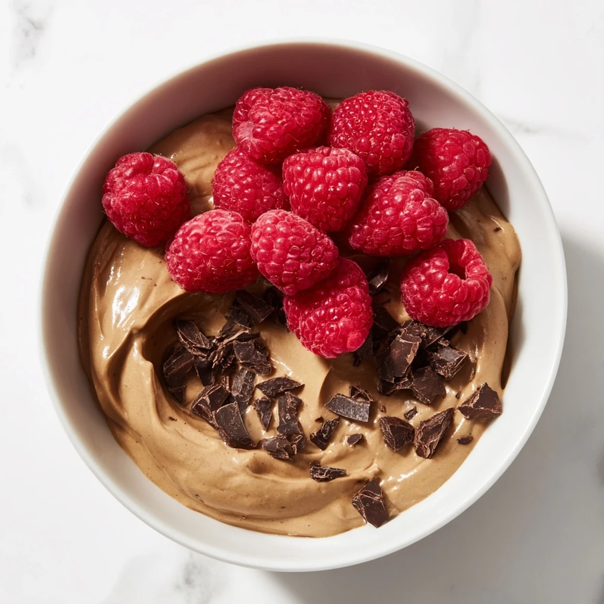 Creamy avocado chocolate mousse recipe: dark, glossy chocolate mousse swirled with fresh berries, ready to eat.
