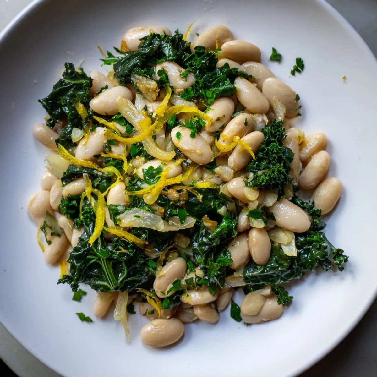 A close-up of the hearty Garlicky Beans with Winter Greens, with vibrant green leaves and garlic.