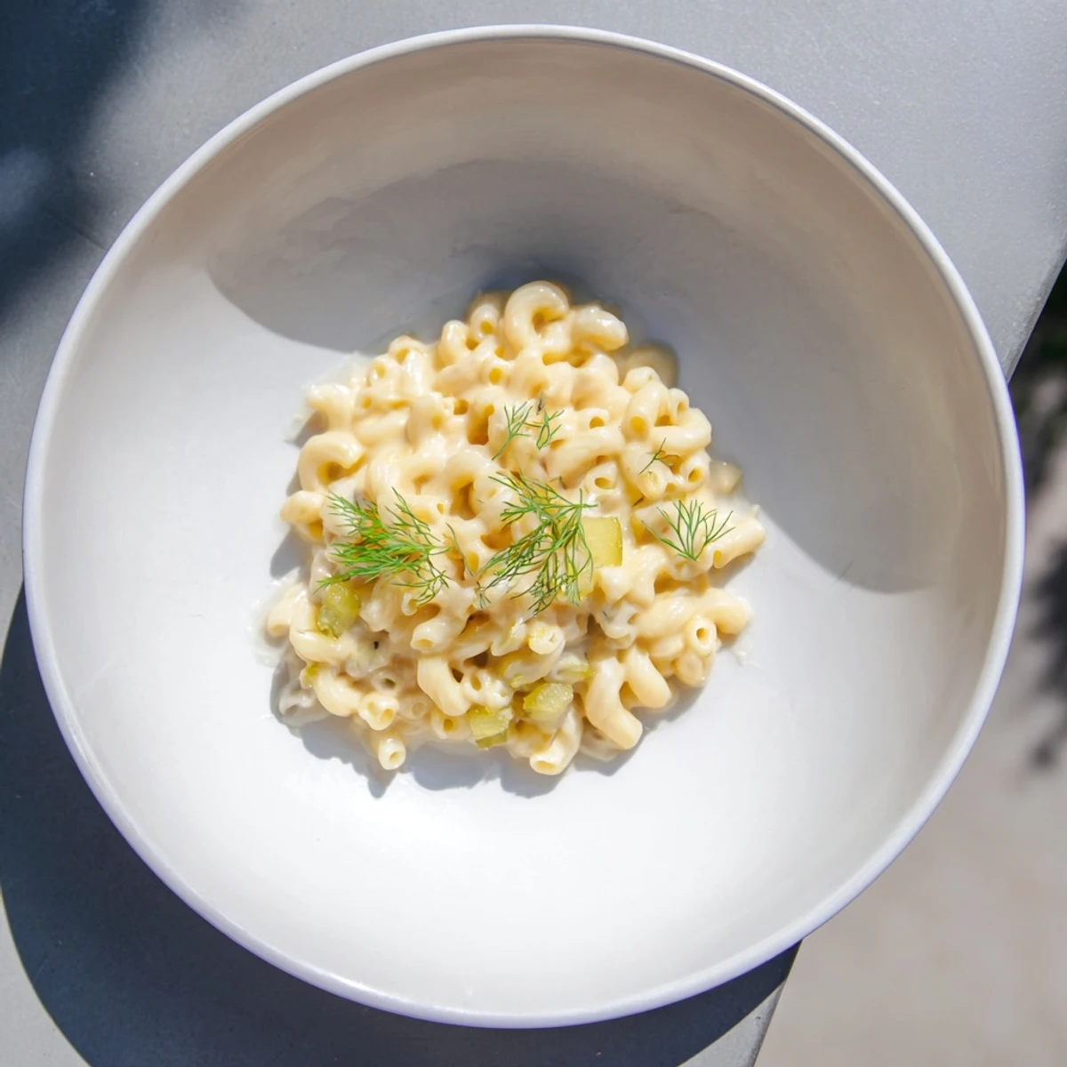 A close-up of creamy Pickle Mac and Cheese, showcasing the dill pickles' vibrant green hue.