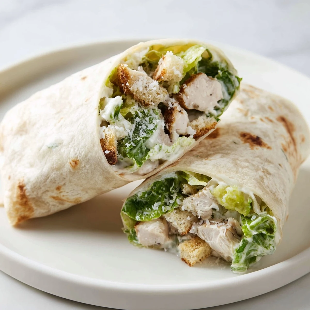 A close-up of a perfectly rolled Chicken Caesar Wrap, ready to eat with the filling spilling.