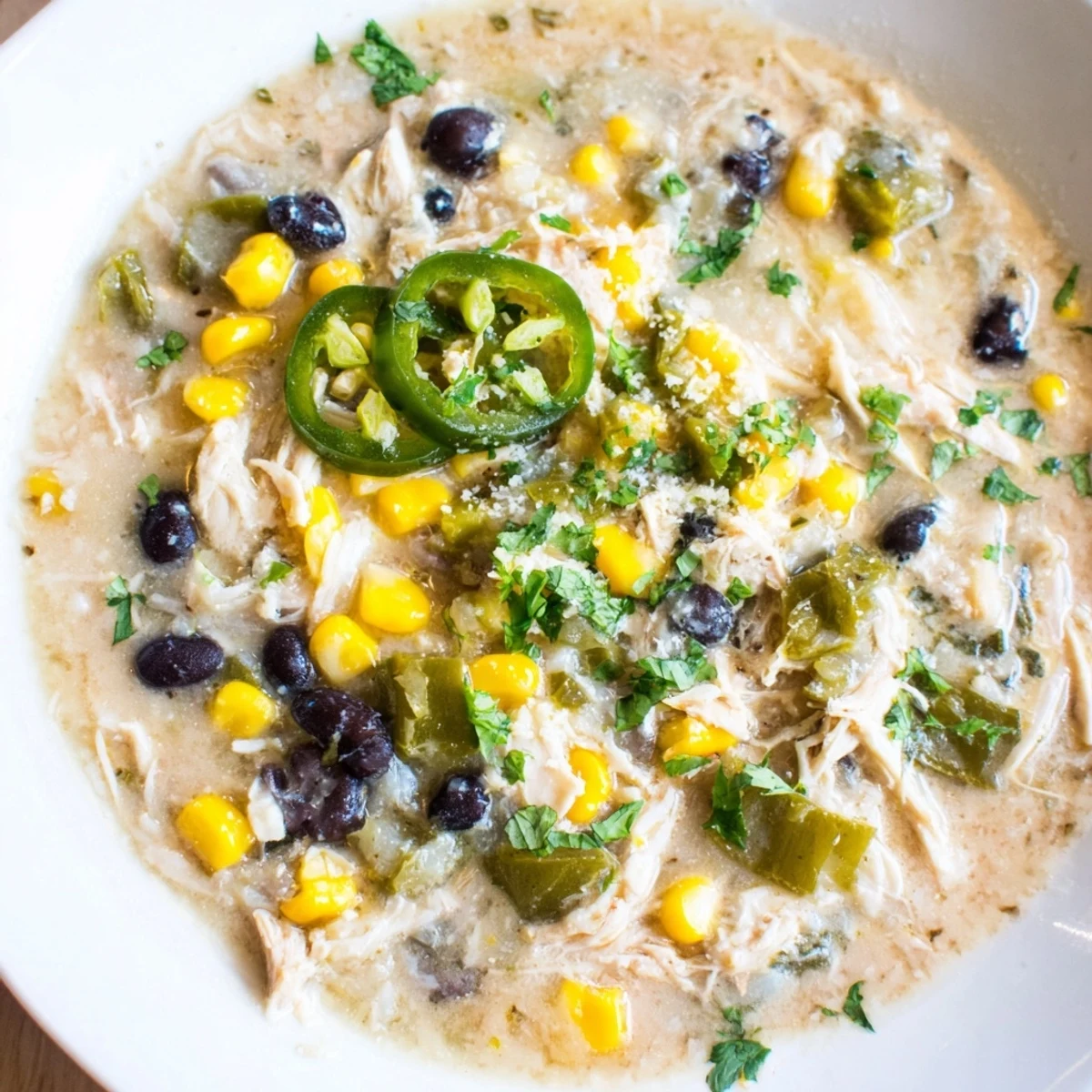 A steaming bowl of Chicken Poblano Soup, featuring visible black beans and corn, perfect for a cozy supper.