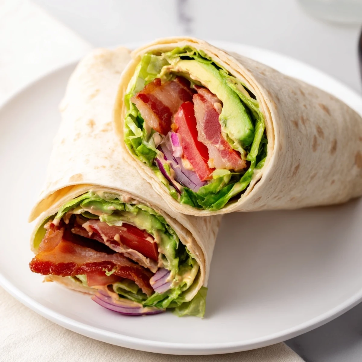 Zesty BLT Wraps with chipotle mayo showcase crispy bacon, fresh tomatoes and romaine lettuce ready to be served.