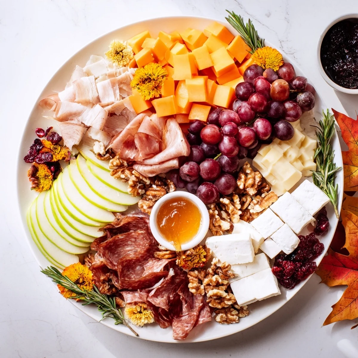 A beautifully arranged maple leaf grazing tray, packed with cheese, charcuterie, and fresh fruits.