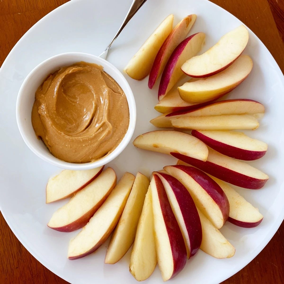 Freshly sliced apples and peanut butter dip arranged, offering a delicious snack combination.