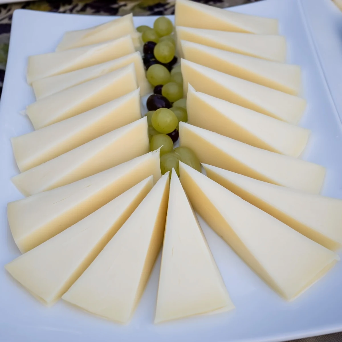 Festive Tannenbaum Border cheese board: thin cheese trees with vibrant green grapes for holiday entertaining.