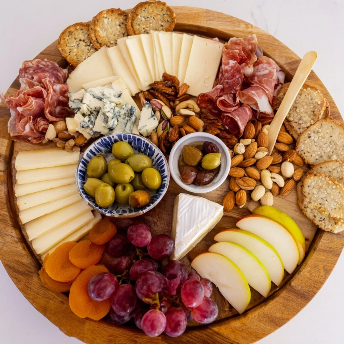 Elegant Gilded Edge cheese board: a close-up of Brie, grapes, and salami arranged artistically on the rim.