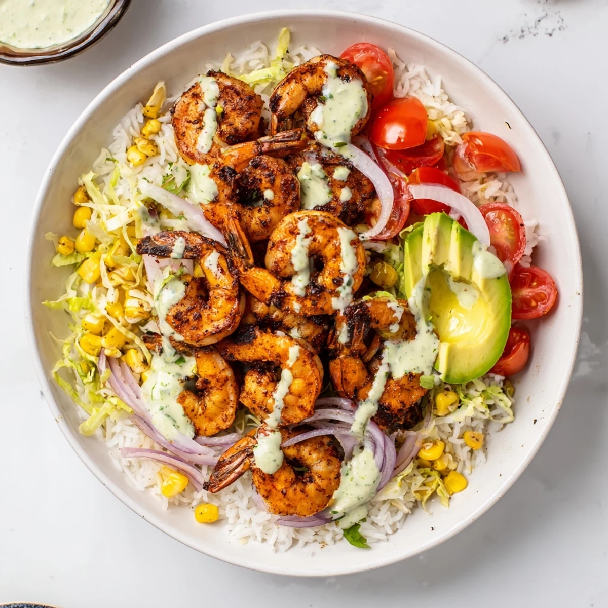 Cajun shrimp taco bowls, filled with spice-rubbed shrimp, colorful veggies, rice, and creamy dressing, look incredibly delicious.