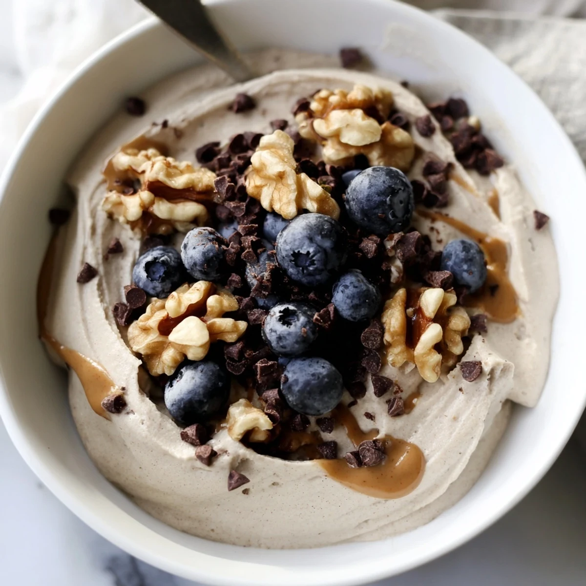 A refreshing Protein Ice Cream Bowl, creamy and sweet, is topped with fresh berries and nuts.