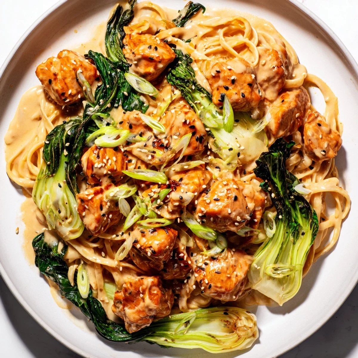 Creamy miso butter salmon pasta, served hot, with glistening sauce and fresh scallions on top.