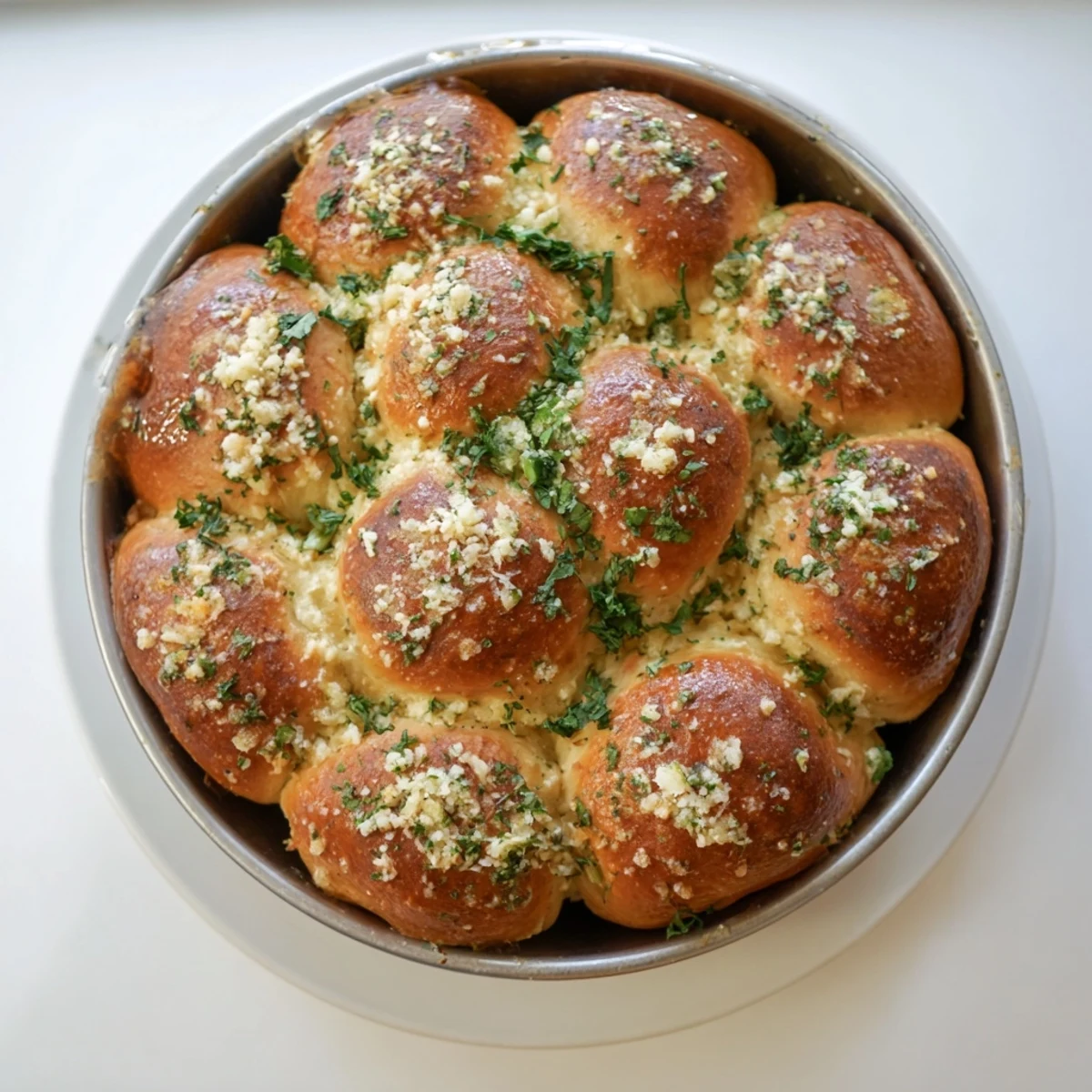 Freshly baked Garlic Butter Bread Pull-Apart rolls, golden brown and glistening with herb-infused butter in a round pan.  