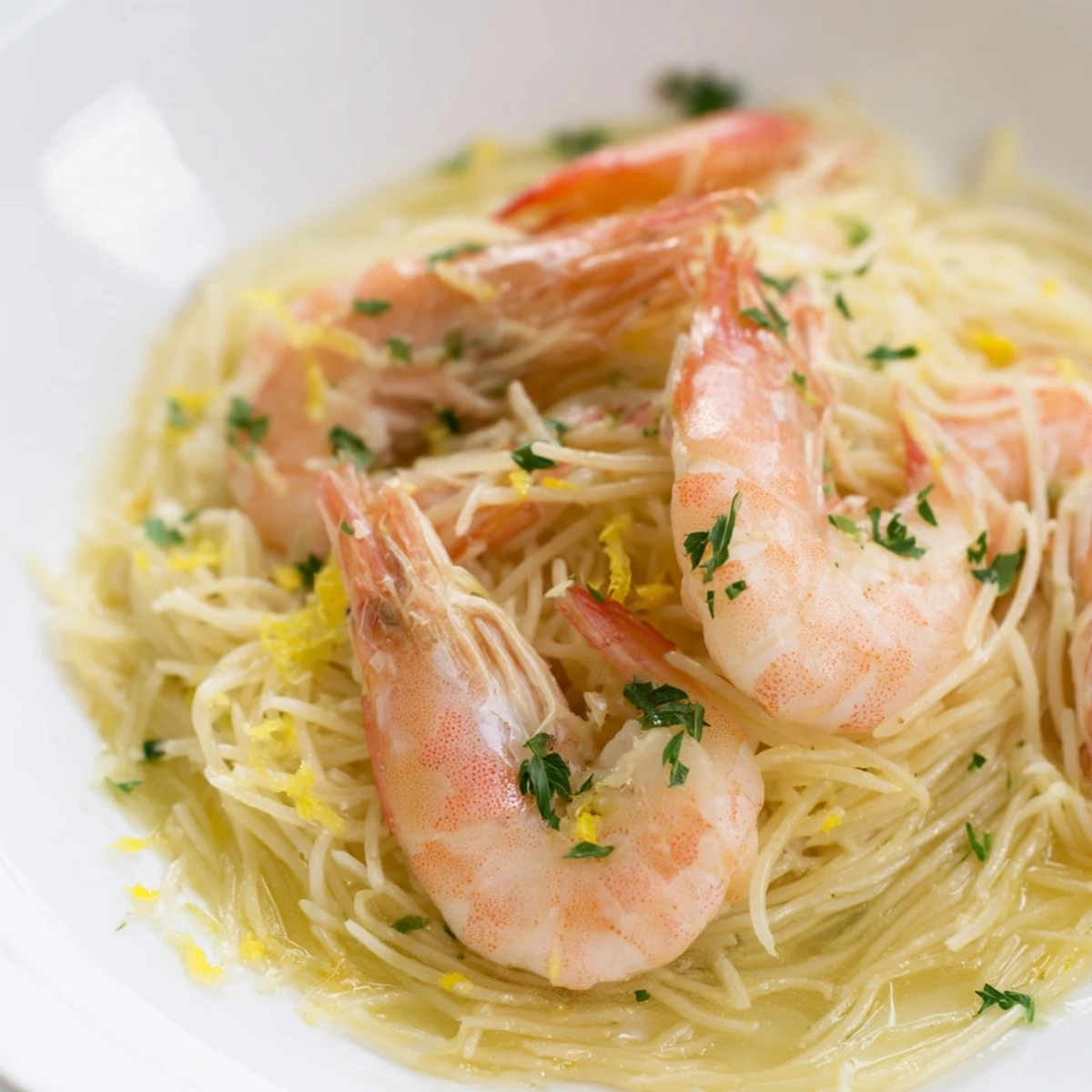 A vibrant plate of Lemon Butter Shrimp Pasta Lite features succulent shrimp tangled in angel hair pasta with a zesty lemon-garlic butter sauce and fresh parsley garnish.