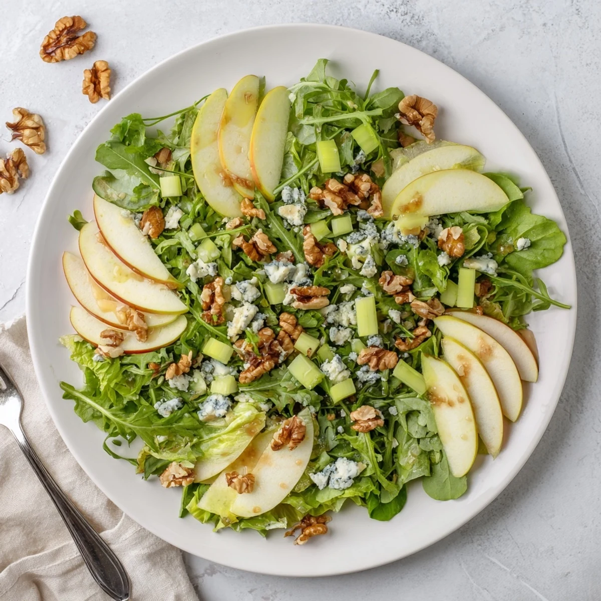 A vibrant Apple and Walnut Salad with sliced apples, walnuts, and a light vinaigrette, served as a refreshing winter side.