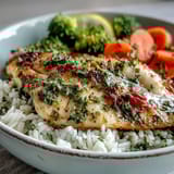 Close-up on golden Baked Tilapia Bowl fillets flaking easily, paired with tender steamed broccoli and carrots over a bed of seasoned rice.