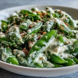 Crisp snap peas and radishes tossed in lemon-tahini dressing, garnished with fresh herbs and sesame seeds.