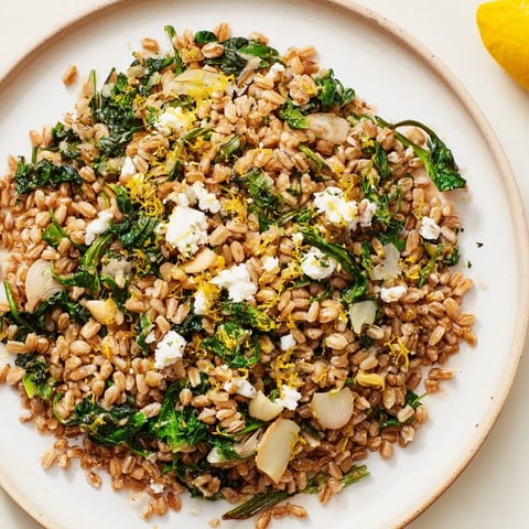 Golden-brown toasted almonds top a warm farro & greens pilaf, ready for serving.