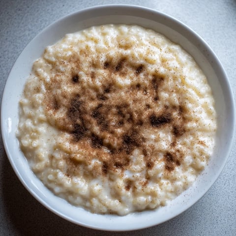 A warm bowl of creamy Rice Pudding with Leftover Rice, sprinkled with sweet cinnamon for serving.