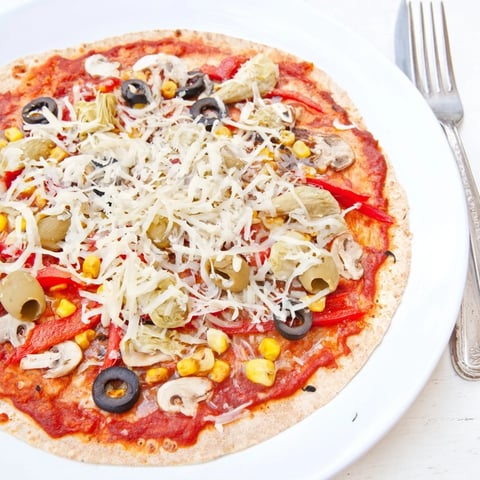 Crispy tortilla pizza, topped with melted cheese and olives, ready to enjoy for a quick dinner.