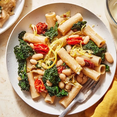 Steaming plate of Healthy Tuscan White Bean & Kale Christmas Pasta, vibrant colors enticing the appetite.