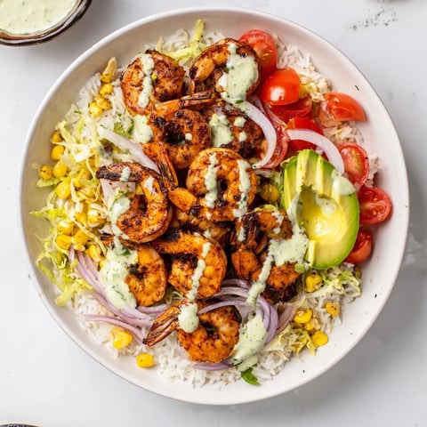 Cajun shrimp taco bowls, filled with spice-rubbed shrimp, colorful veggies, rice, and creamy dressing, look incredibly delicious.
