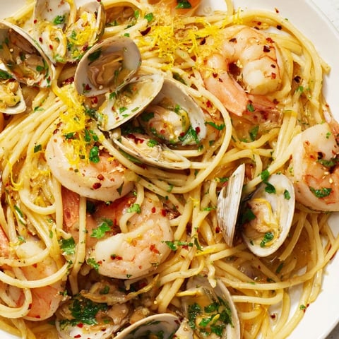 Steaming Seafood Pasta Aglio e Olio, overflowing with clams, shrimp, and garlic, ready to eat.