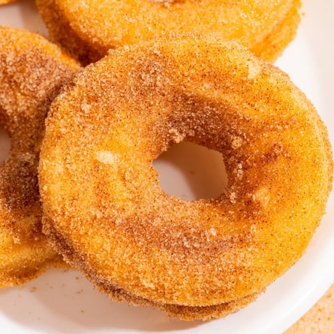 Warm golden Air Fryer Cinnamon Sugar Donuts, freshly air-fried to fluffy perfection, coated in sparkling cinnamon sugar and ready to enjoy with coffee.