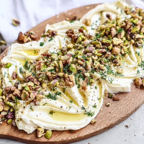 Creamy Flavored Butter Board Charcuterie spread on a wooden board, topped with honey, nuts, and fresh herbs.