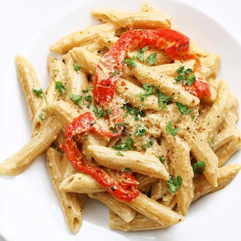Creamy Cajun pasta with al dente penne, roasted red bell peppers, and a rich, smoky sauce garnished with fresh parsley.  