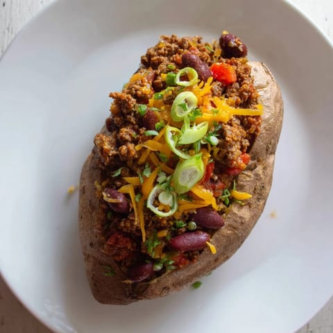 A close-up shot of hearty Chili-Style Baked Potatoes, showing the texture of the fluffy baked potato filled with chili.