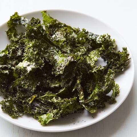 Freshly baked kale chips, tossed with spices, offering a satisfying, crisp texture and flavorful goodness.