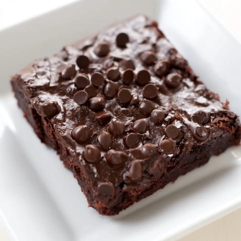 A plate of moist, gluten-free black bean brownies shows off a rich, dark texture bursting for a bite.