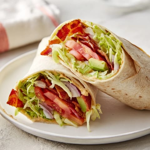 Freshly assembled Zesty BLT Wraps with creamy chipotle mayo reveal layers of delicious ingredients bursting.