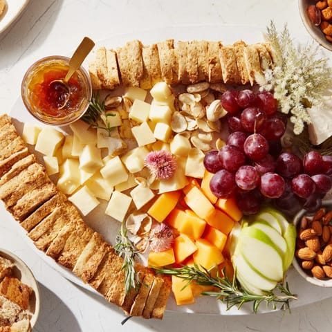Golden wheat bundle board overflowing with colorful fruits, assorted cheeses, and savory accompaniments.