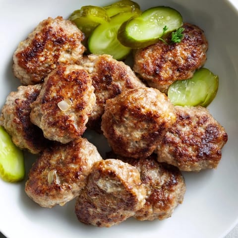 Close-up of juicy, savory Danish frikadeller, served with vibrant pickles, perfect for a cozy dinner.