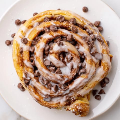 Soft, pillowy cinnamon rolls filled with creamy Nutella and melty chocolate chips, served warm for a decadent breakfast treat.