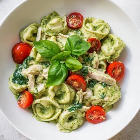 A hearty skillet meal featuring tender cheese tortellini, wilted spinach, and juicy chicken coated in rich, garlicky basil pesto.