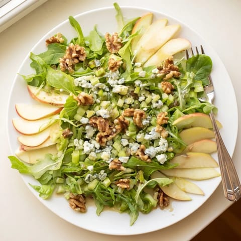 Crisp apple slices and toasted walnuts tossed with mixed greens and a tangy vinaigrette, ready to serve as a light appetizer.  