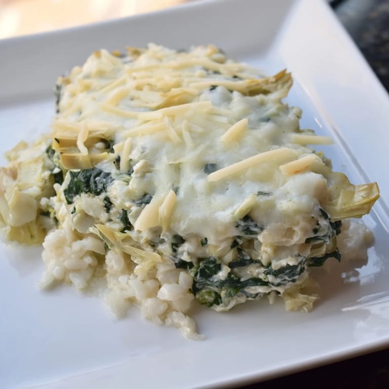 Creamy Cheesy Spinach and Artichoke Bake, ready to scoop, featuring visible artichoke pieces and melted mozzarella.