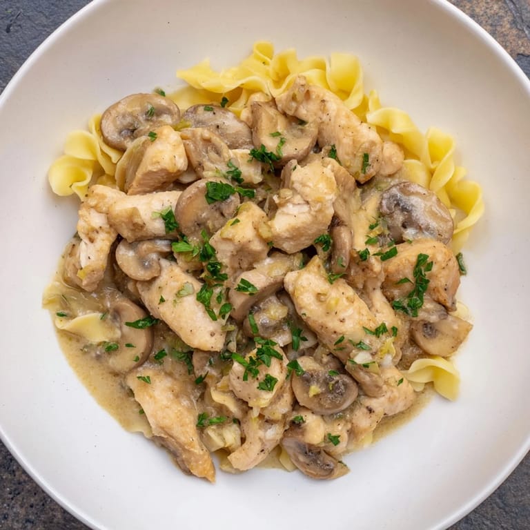 A steaming bowl of Creamy Chicken Stroganoff, the rich sauce clinging to tender chicken and mushrooms.