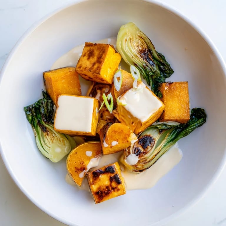 Golden-brown miso-glazed tofu with roasted squash, drizzled with savory sauce and scallions.