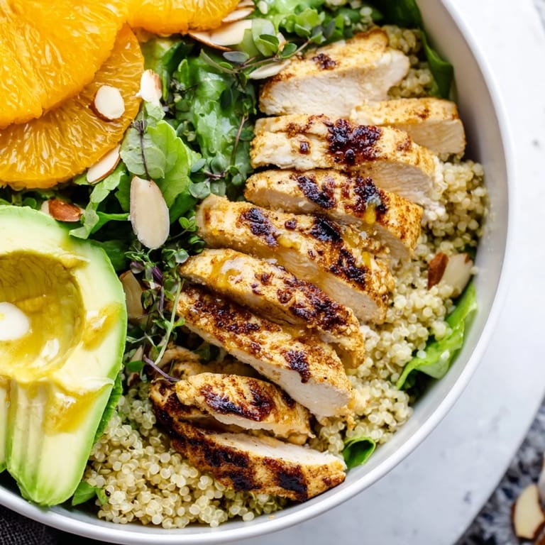 Colorful Citrus Herb Chicken Salad Bowl plated with toasted almonds, red onion, and a refreshing mix of arugula and spinach for a healthy lunch.