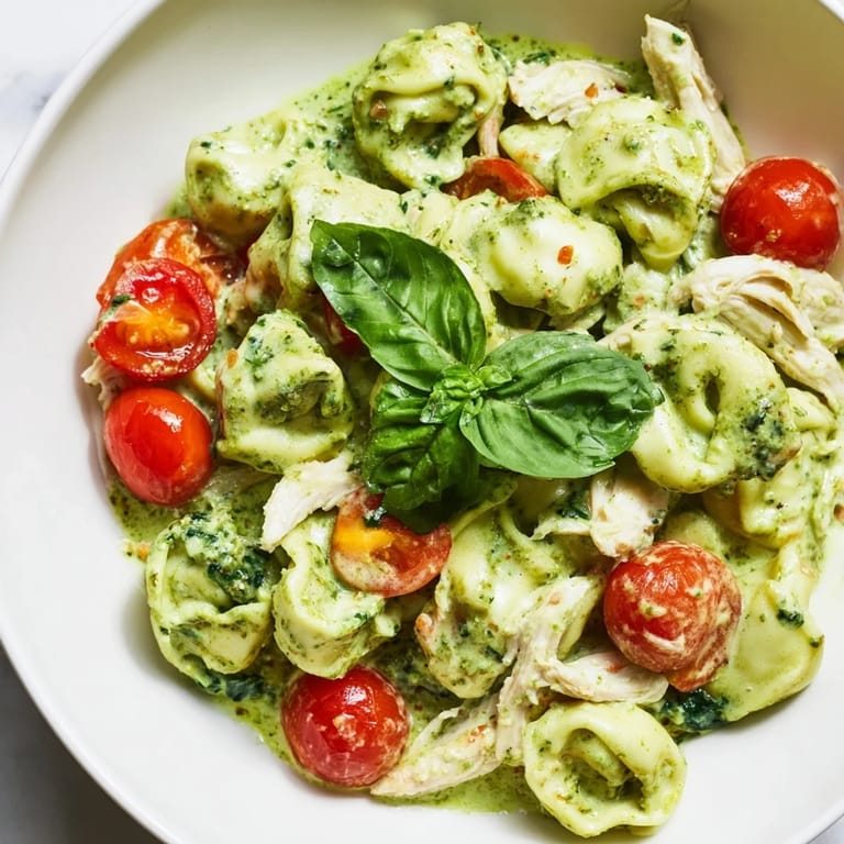 Close-up of Creamy Pesto Tortellini Skillet with twirled pasta, golden Parmesan, and halved cherry tomatoes for a colorful family dinner.