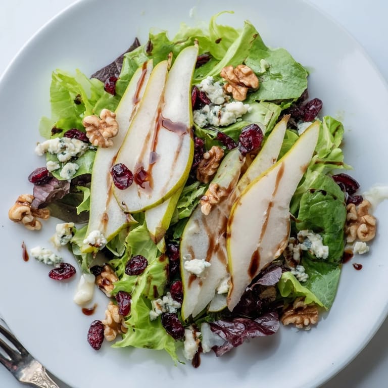 Juicy pear slices and tangy gorgonzola shine on mixed greens with walnuts in a pear gorgonzola salad.